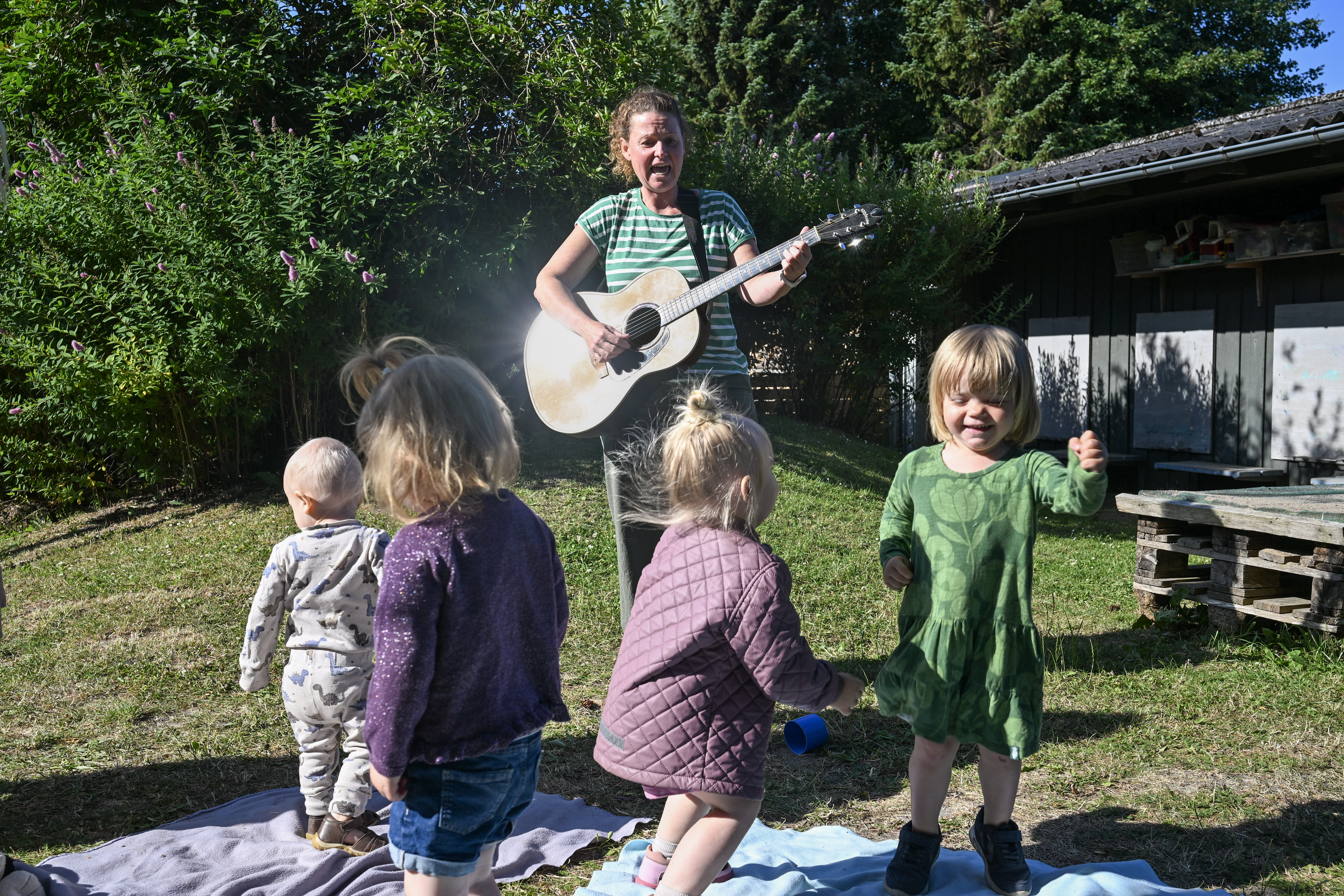 Børn og voksen danser og spiller guitar