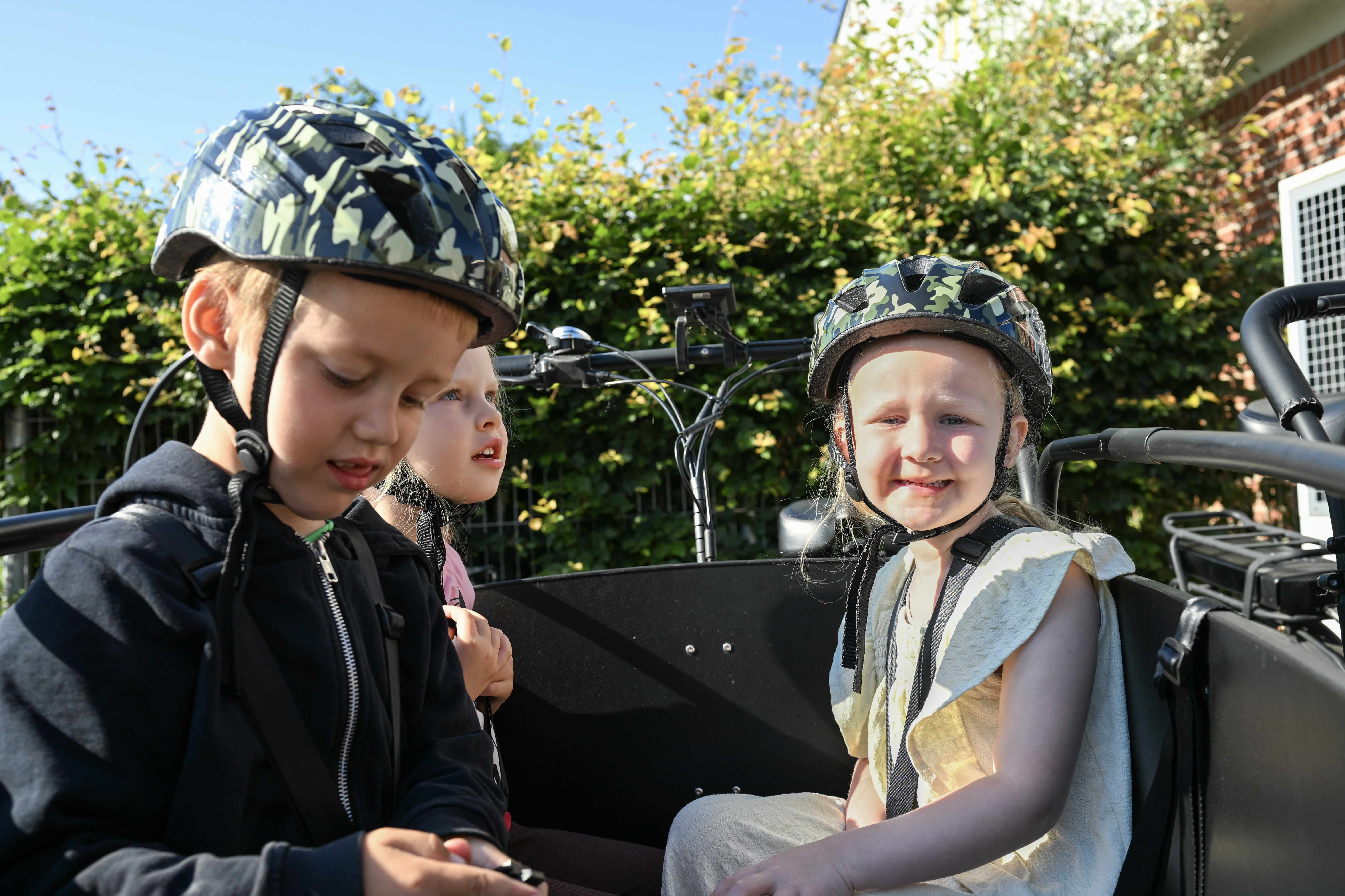 Børn i ladcykel med cykelhjelme på