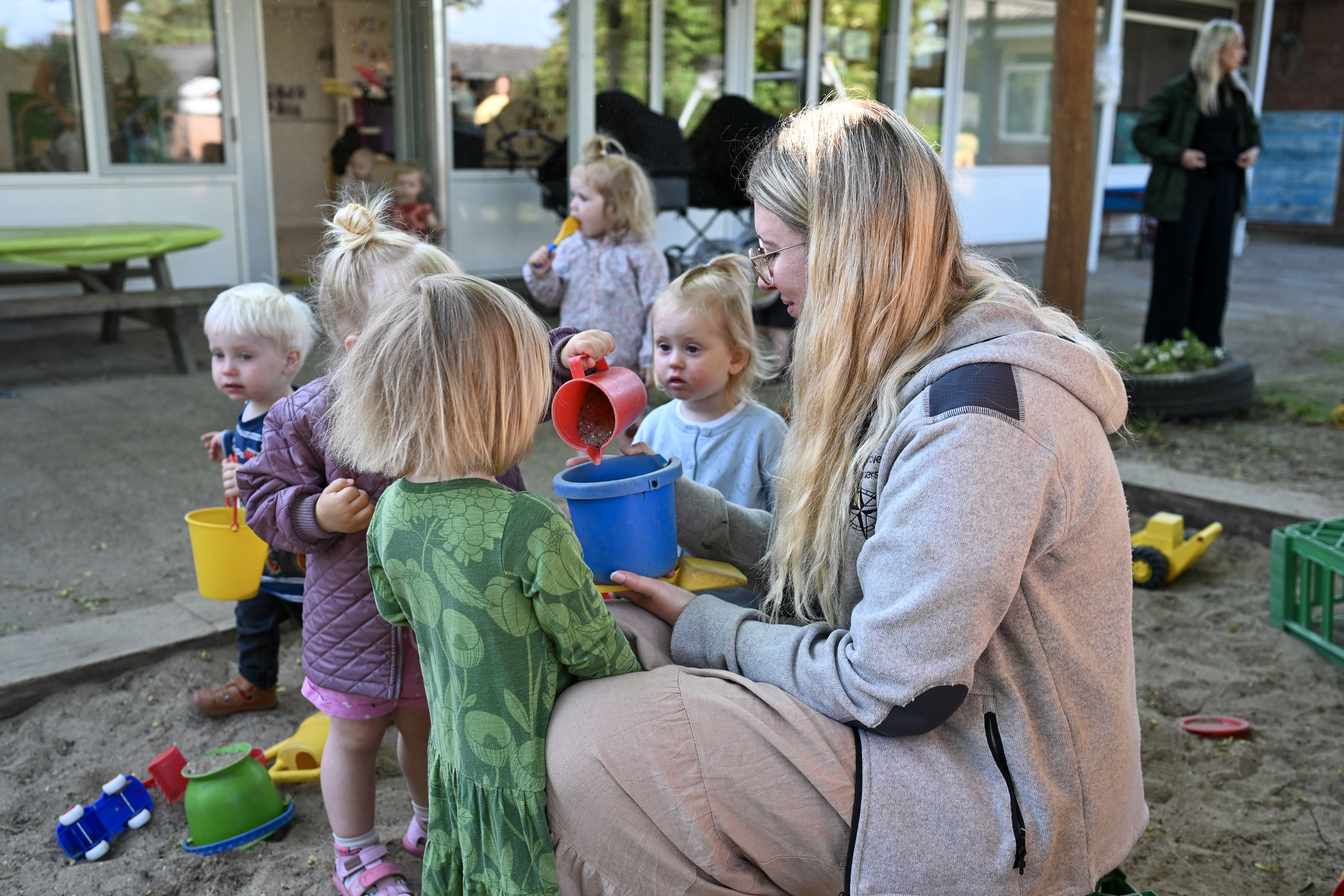 Børn og pædagog leger i sandkasse